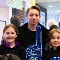 Siblings smiling for a picture with their foam fingers up